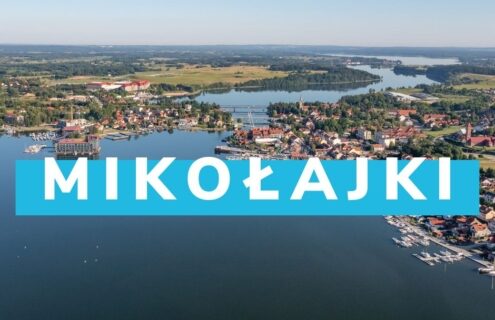 Panorama Mikołajek z widokiem na jeziora, port i zabudowania, idealne miejsce na wypoczynek i sporty wodne.